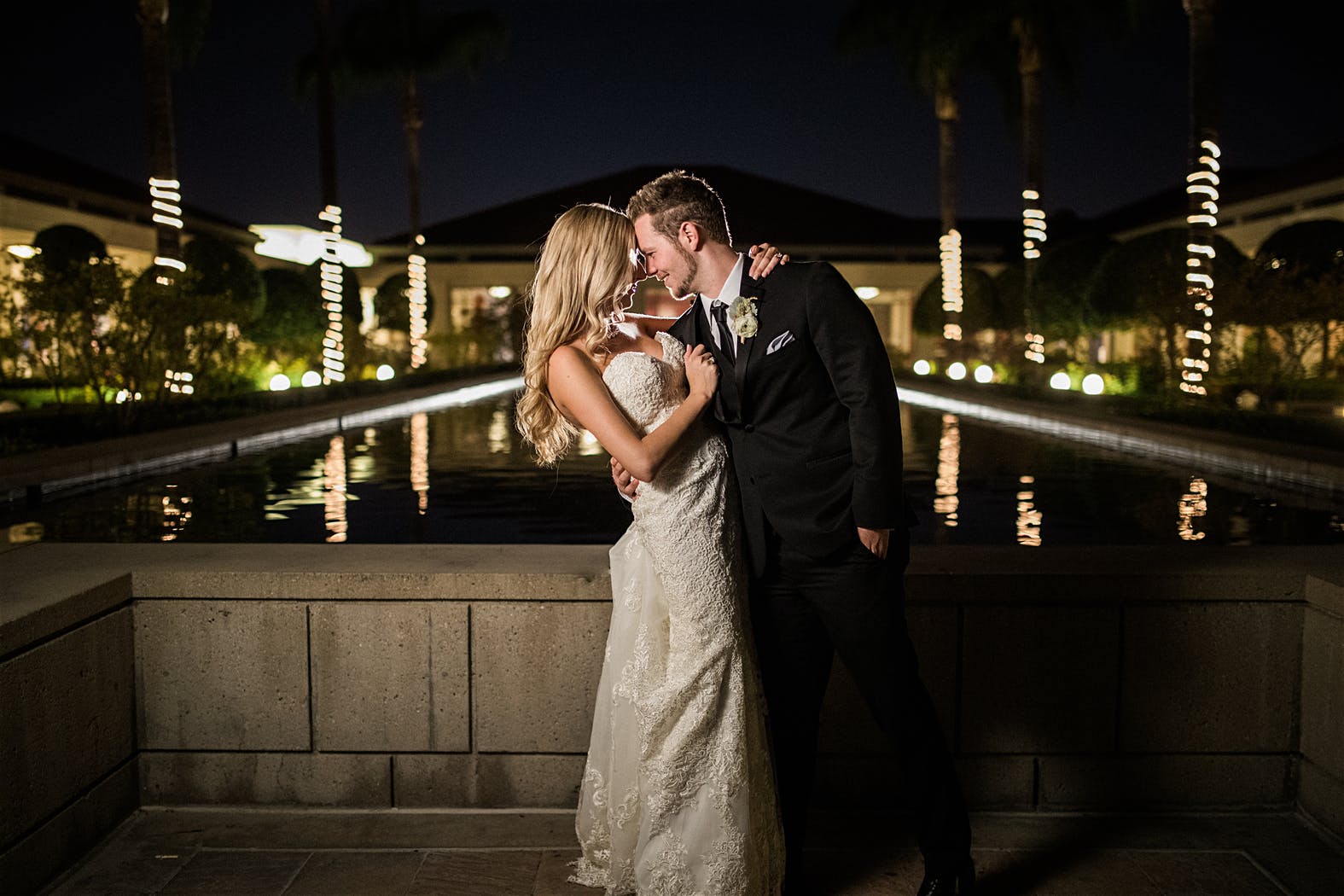 Bride and Groom cuddle up for night photos in front of the reflecting pool at The Richard Nixon Library wedding venue in Yorba Linda.